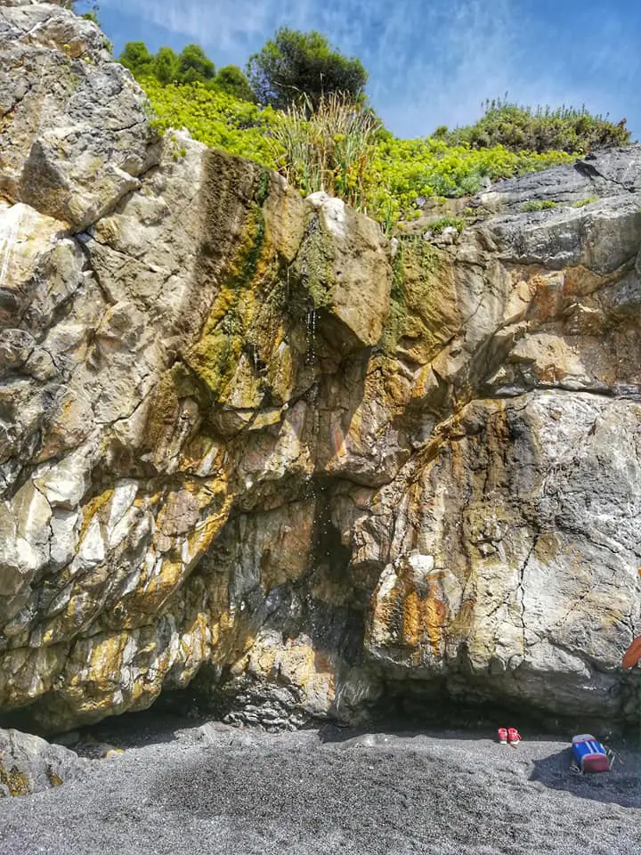 Rocce e una cascatella al margine della spiaggia