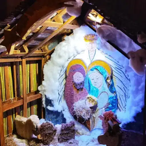Presepe con la Sacra Famiglia in mosaico e neve di cotone in un paese della Toscana