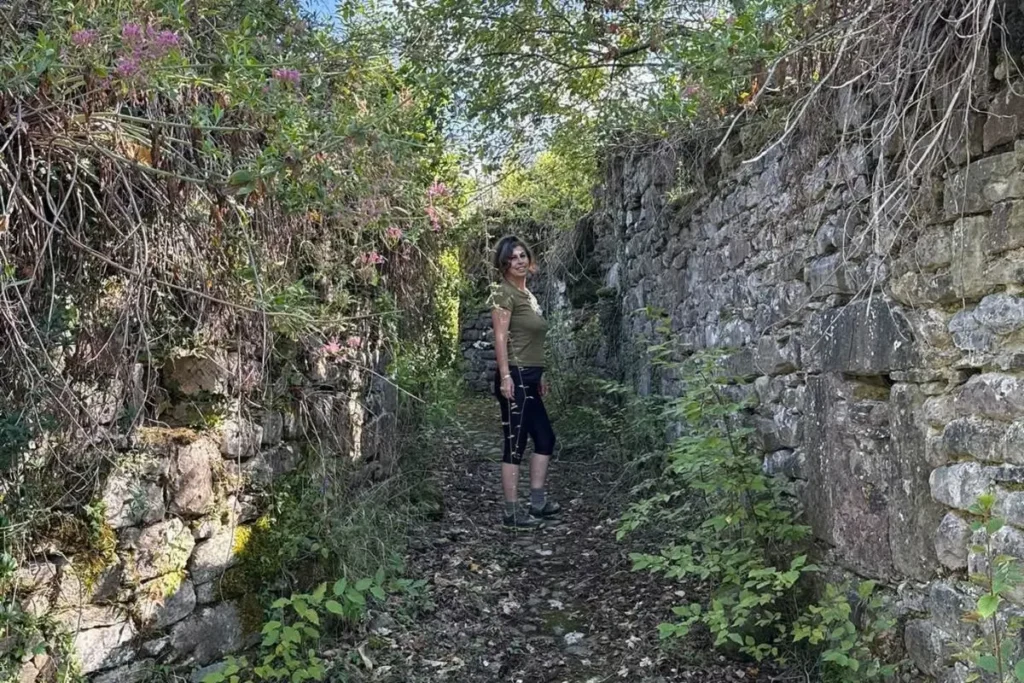 Sabrina, autrice e guida, cammina tra i ruderi del borgo fantasma di Bergiola di Minucciano